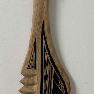Carved wooden decorative paddle with black patterns